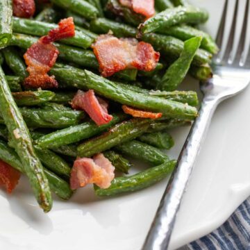 Green beans and bacon on a white plate.