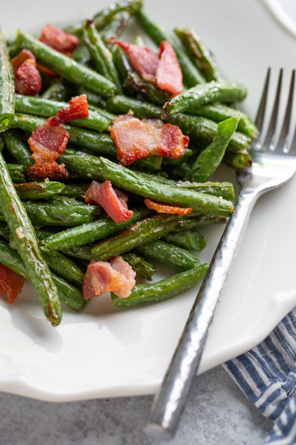 Green beans and bacon on a white plate.