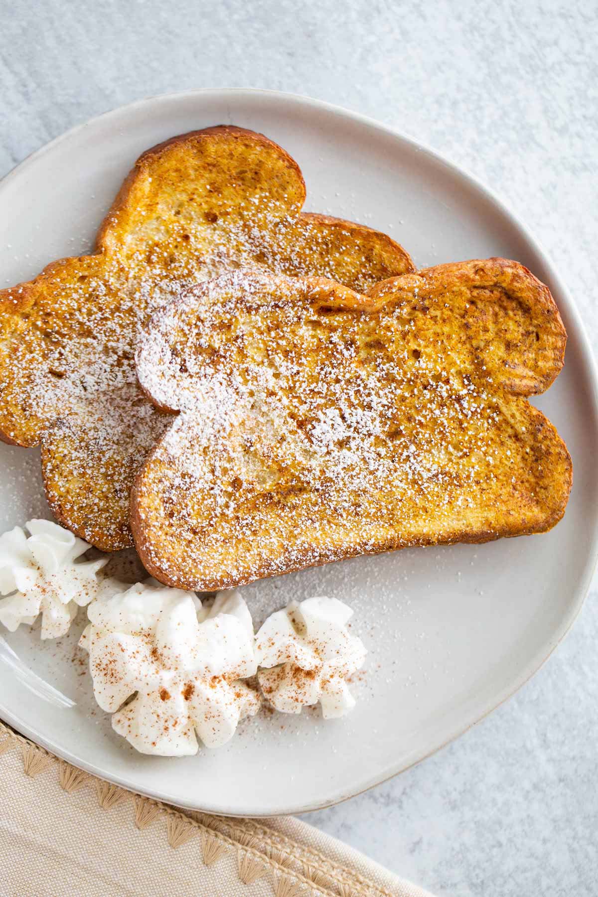 Pumpkin French toast on a plate with whipped cream.