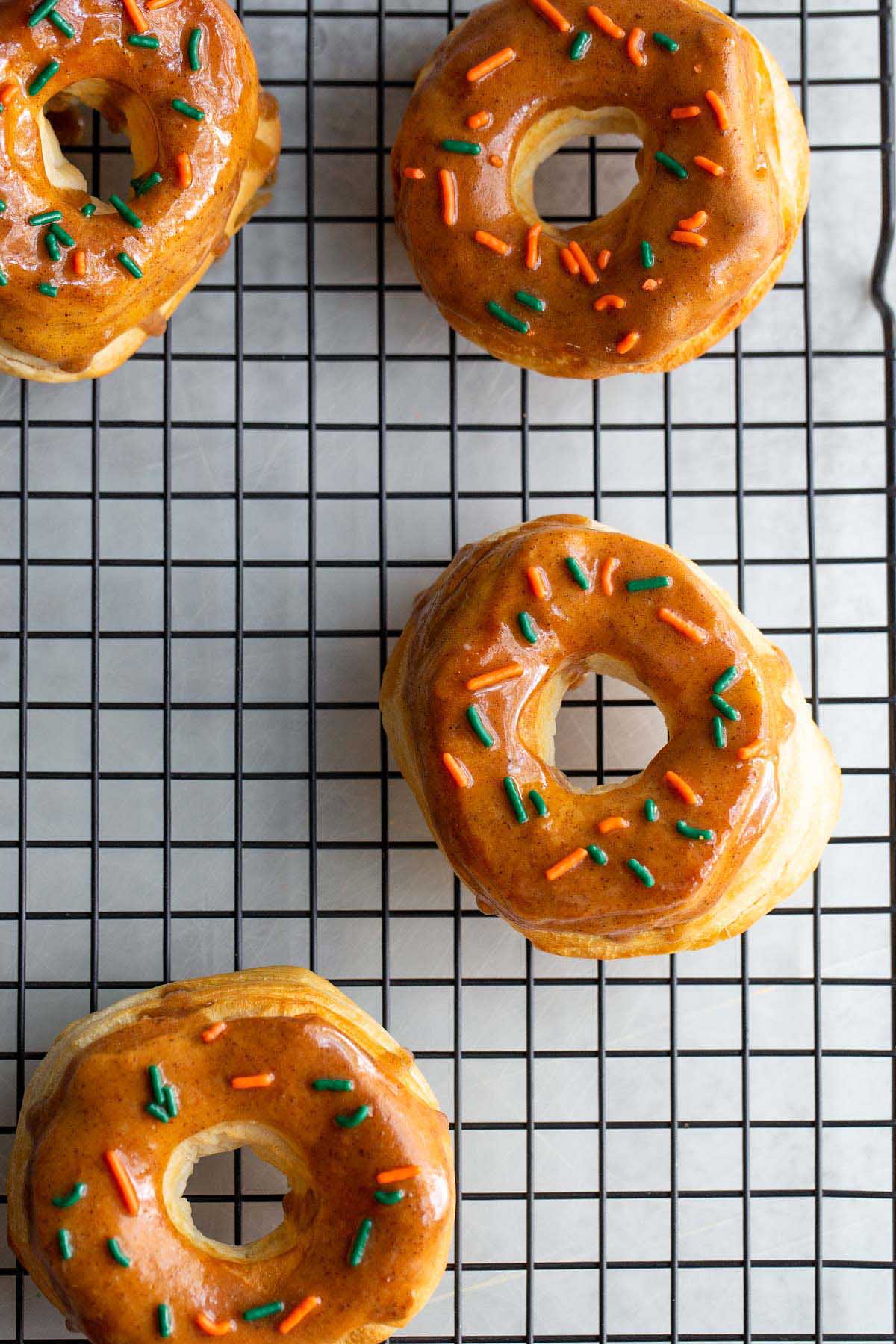 donuts on a cooling rack with glaze and sprinkles