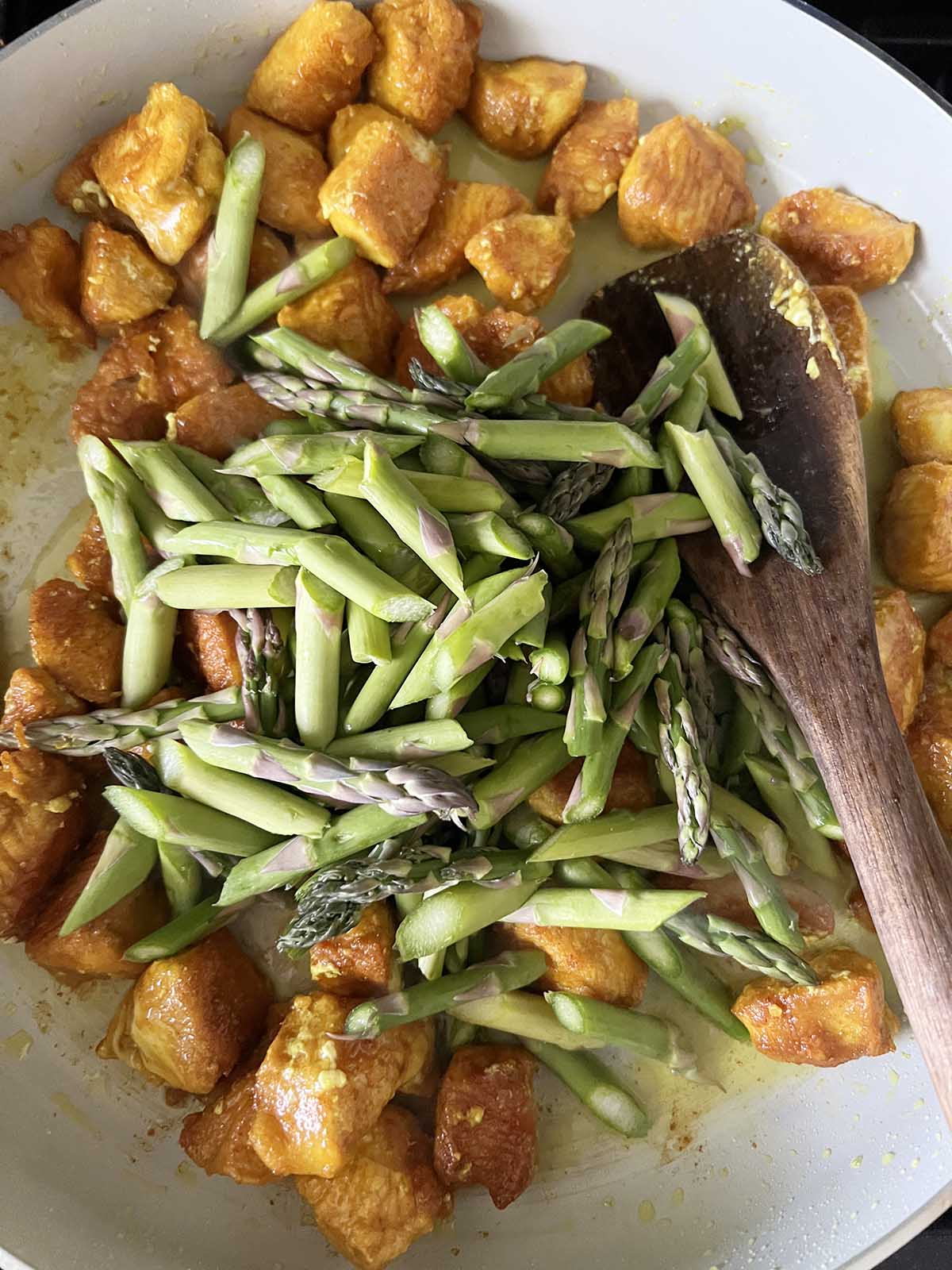 Chicken and asparagus in a skillet.