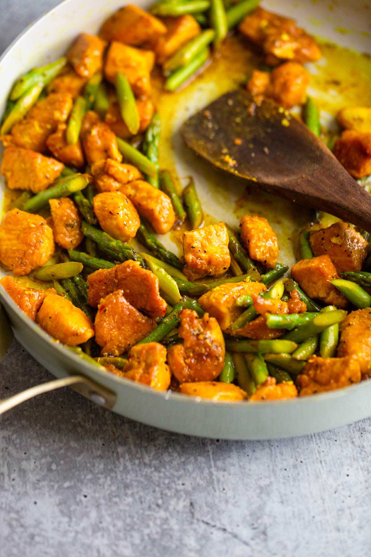 Turmeric chicken and asparagus in a skillet.