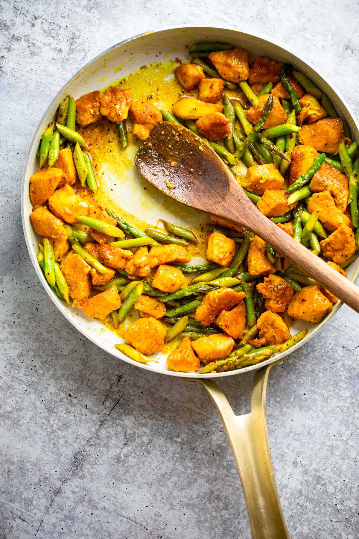 Turmeric chicken and asparagus in a skillet.