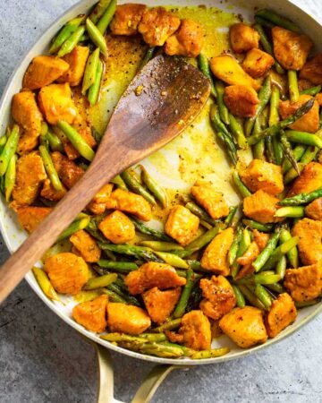 Turmeric chicken and asparagus in a skillet.