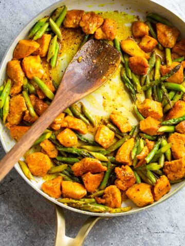 Turmeric chicken and asparagus in a skillet.