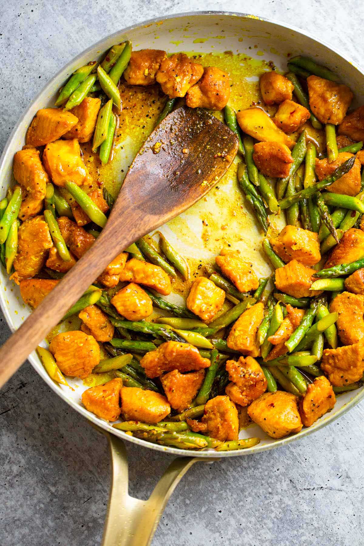 Turmeric chicken and asparagus in a skillet.