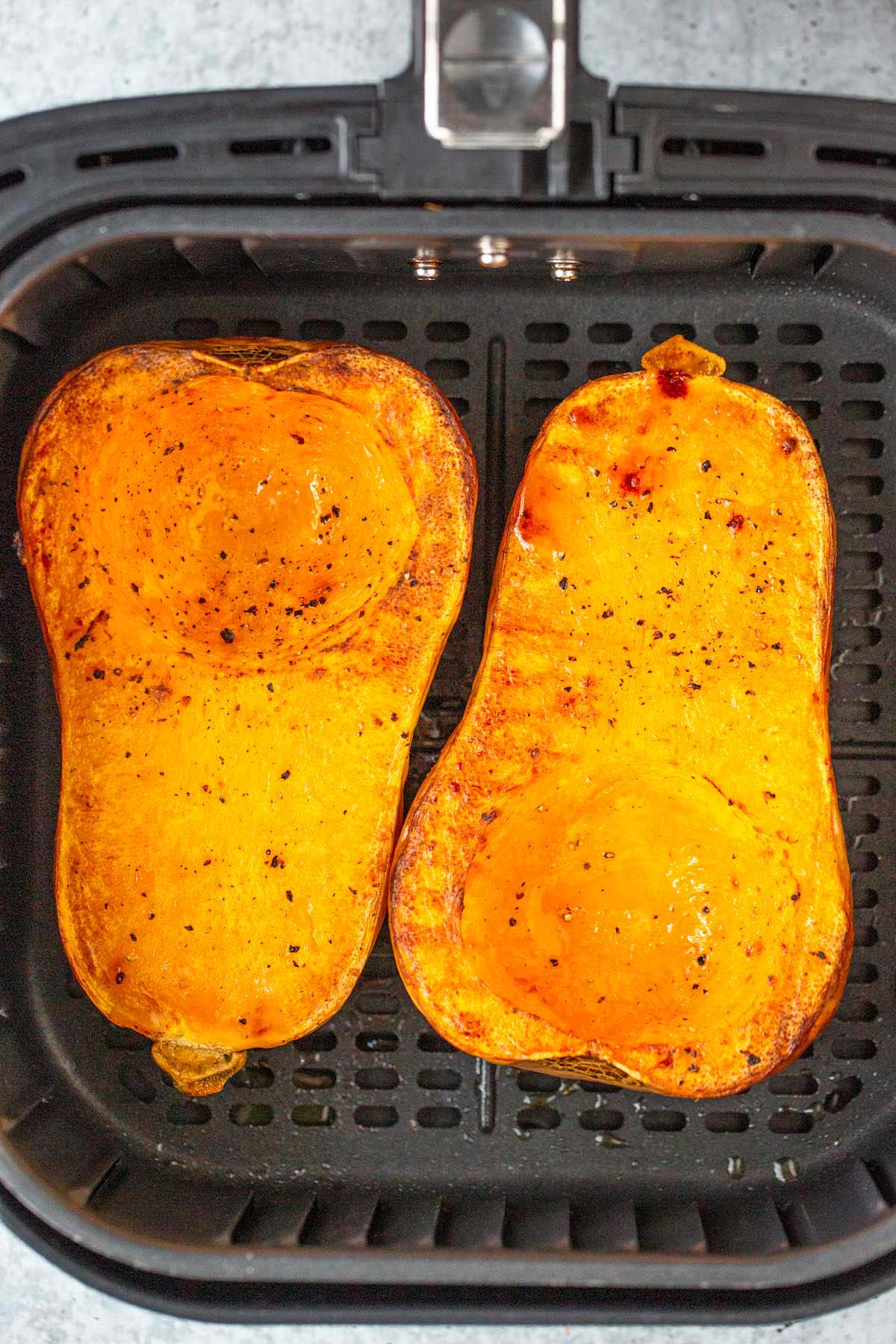 Cooked butternut squash halves in air fryer.