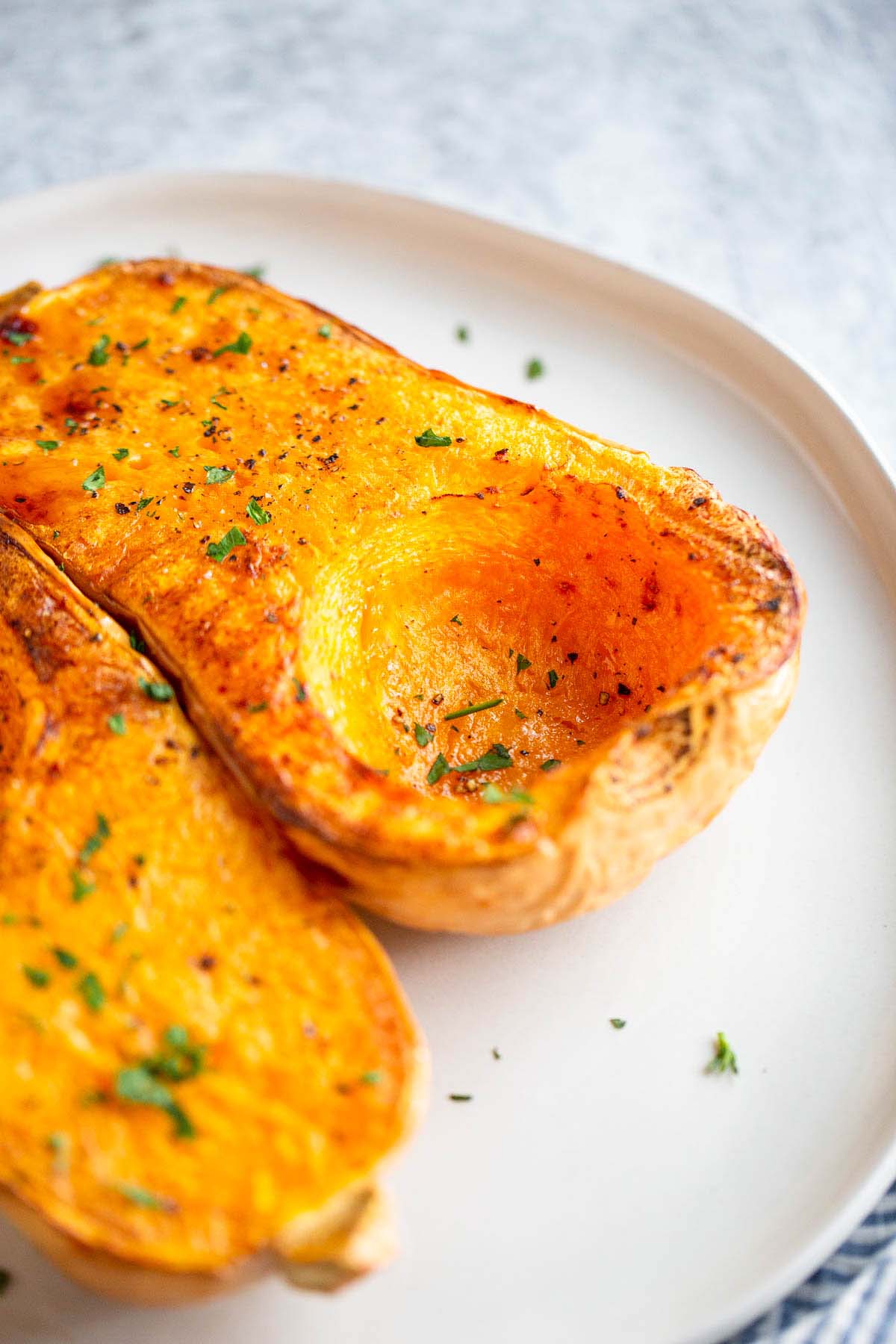 Butternut squash halves on a plate with chopped parsley.