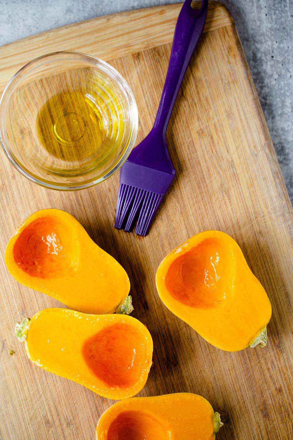 Brushing honeynut squash with olive oil.