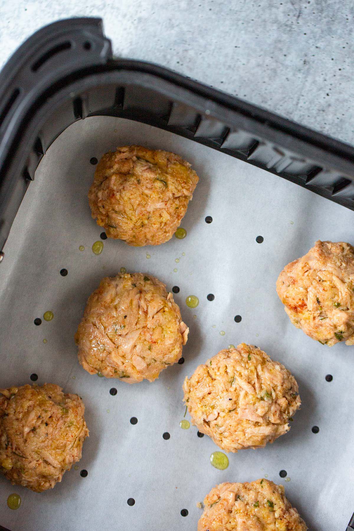 Uncooked tuna patties in air fryer basket.