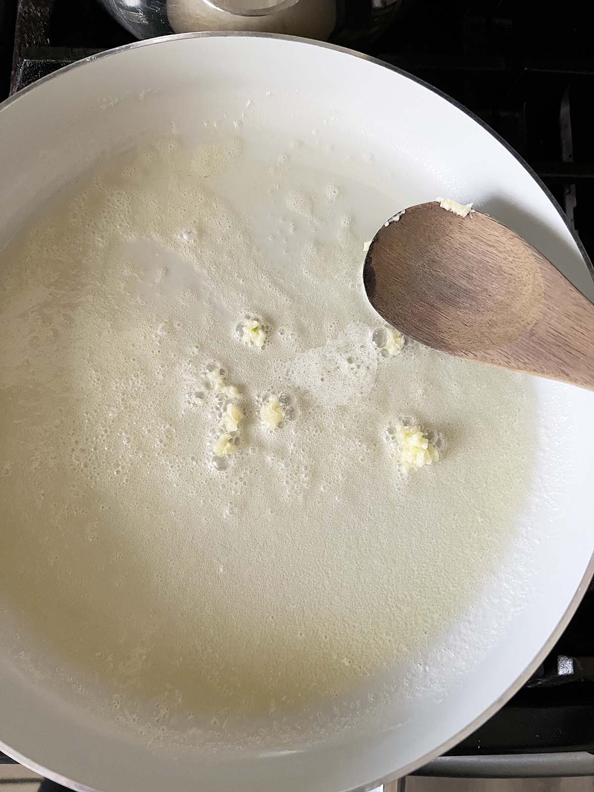 Adding minced garlic to the pan.