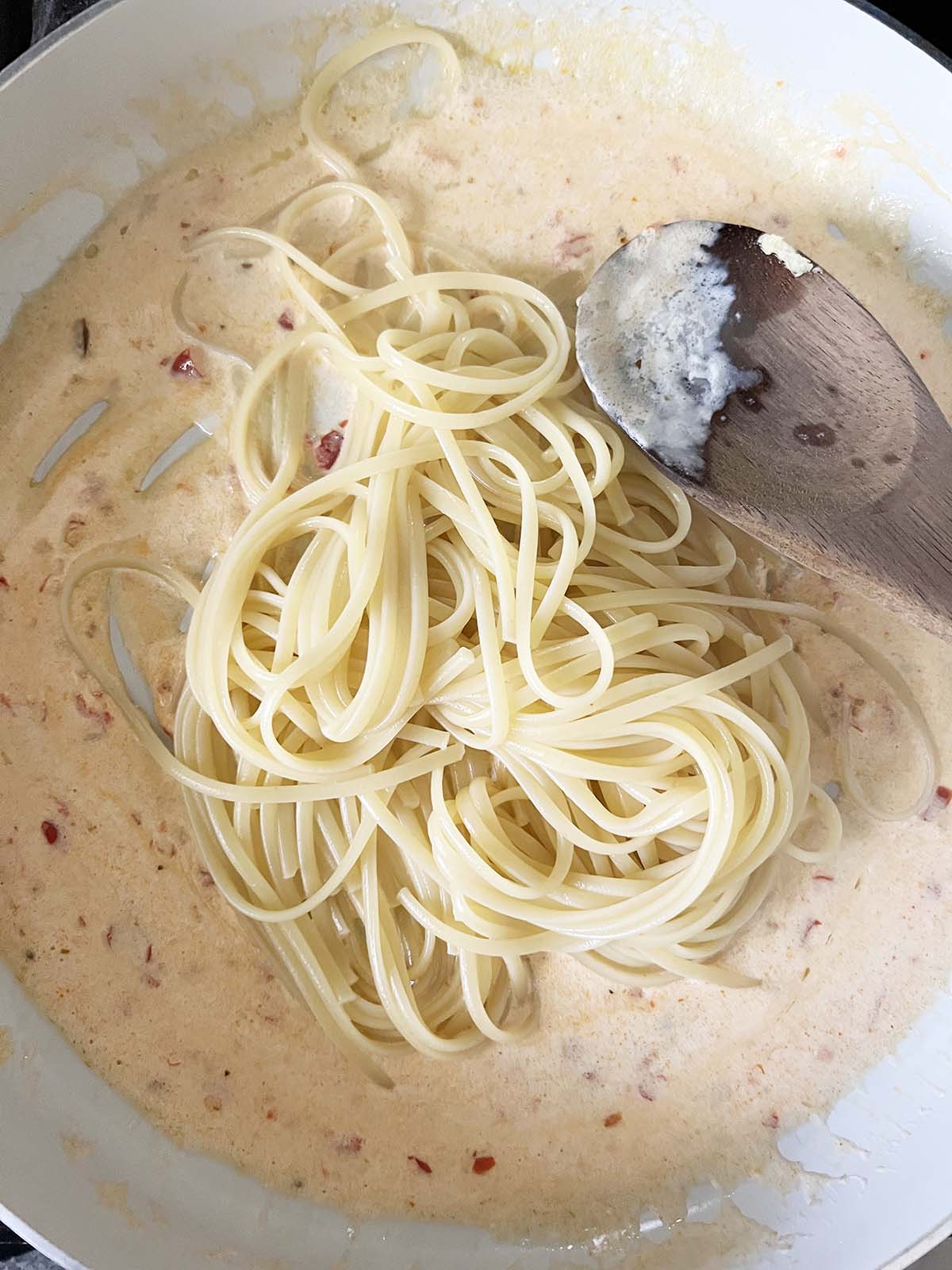 Adding pasta to a creamy sauce.