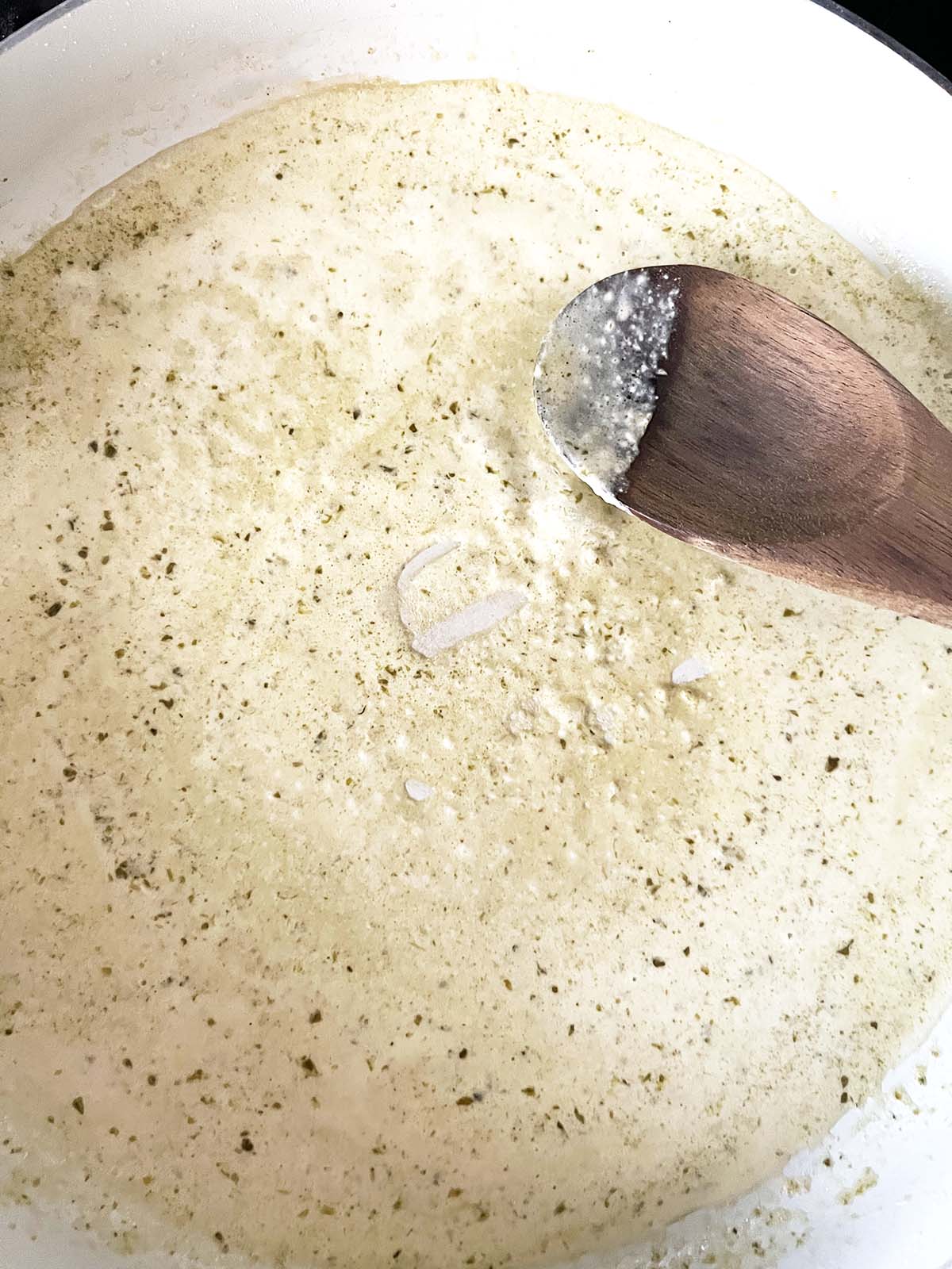 Making a cream sauce with pesto and seasonings.