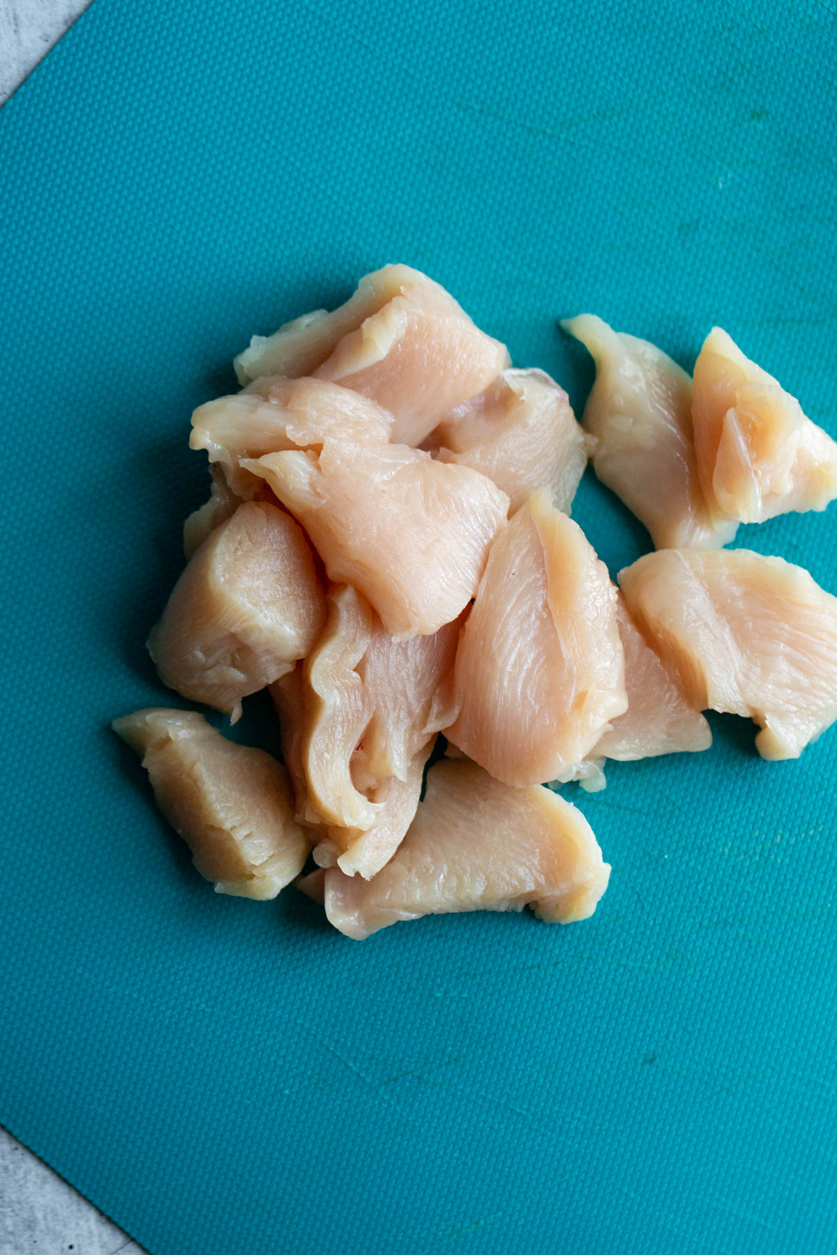 uncoooked chicken pieces on a blue cutting board