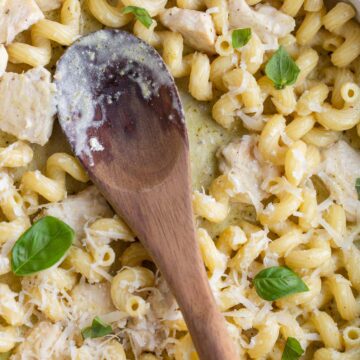 Creamy pesto cavatappi in a skillet with a wooden spoon.