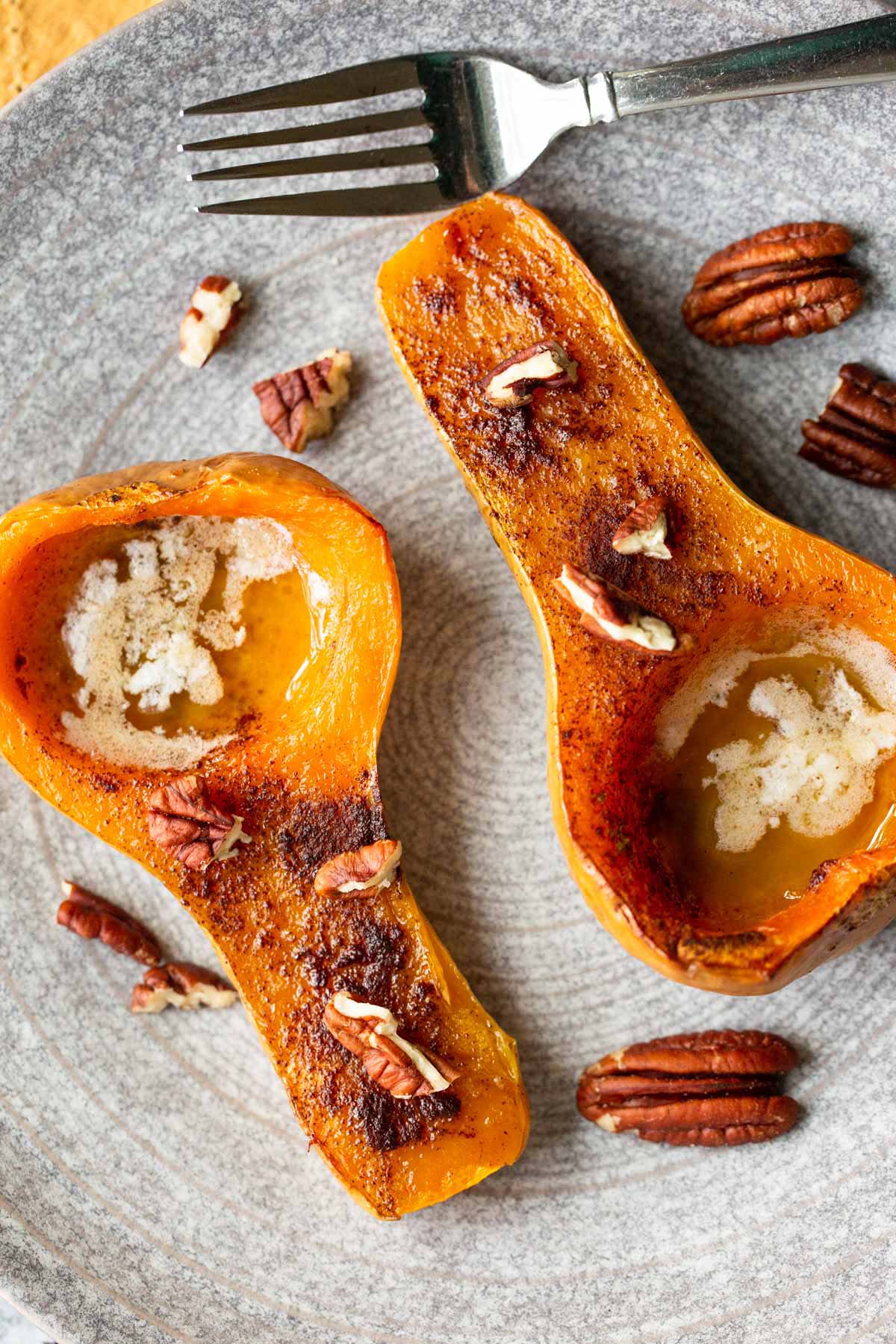 Honeypatch squash topped with pecans and a fork on a grey plate.