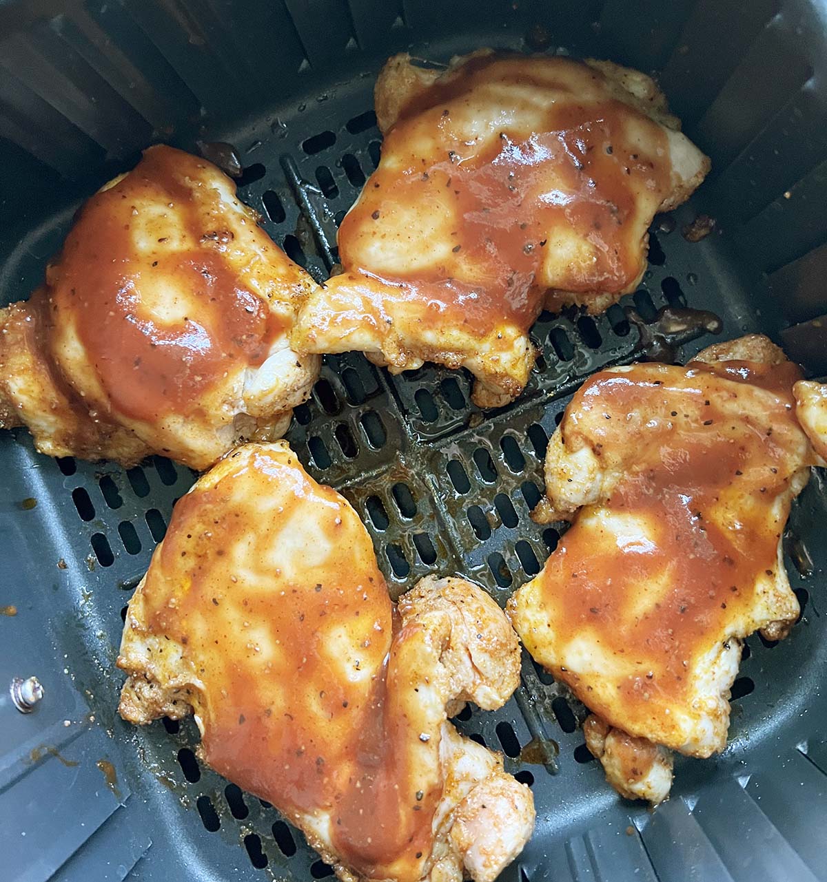 Adding bbq sauce to chicken thighs.