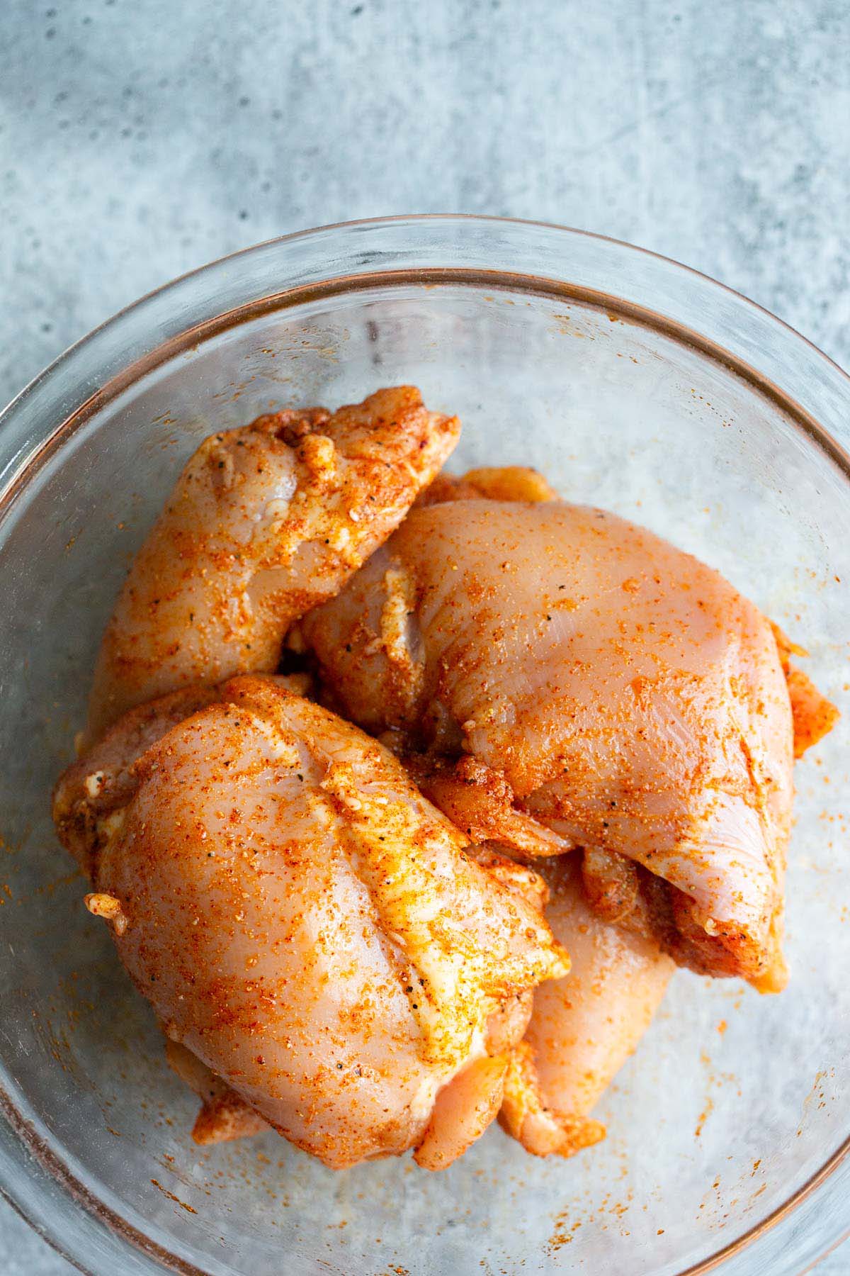 Uncooked chicken thighs in a bowl.