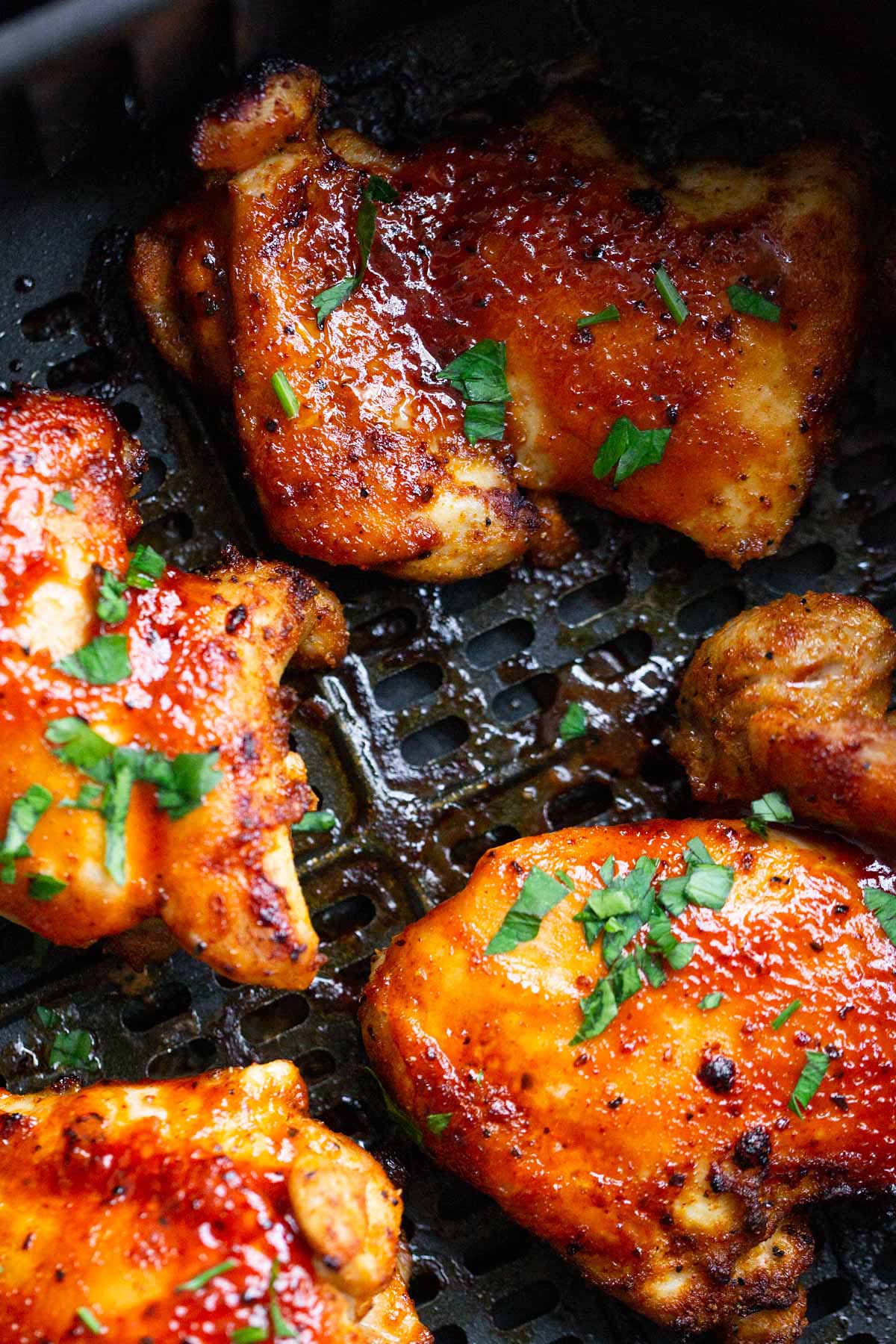 BBQ chicken thighs in air fryer basket.