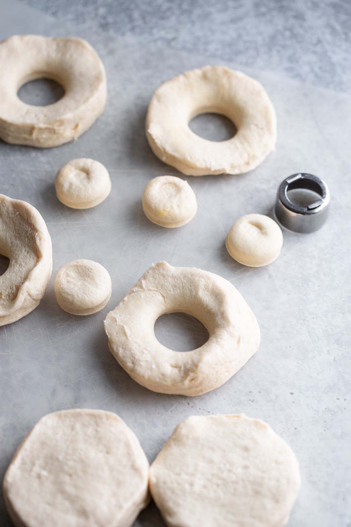 Punching holes in donuts to make biscuits.