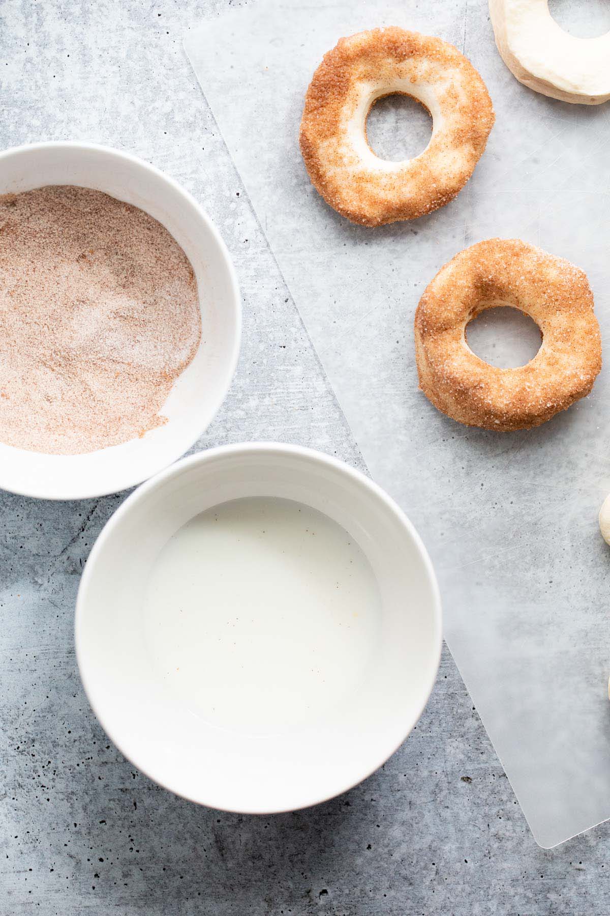 Dipping uncooked donuts in cinnamon and sugar.