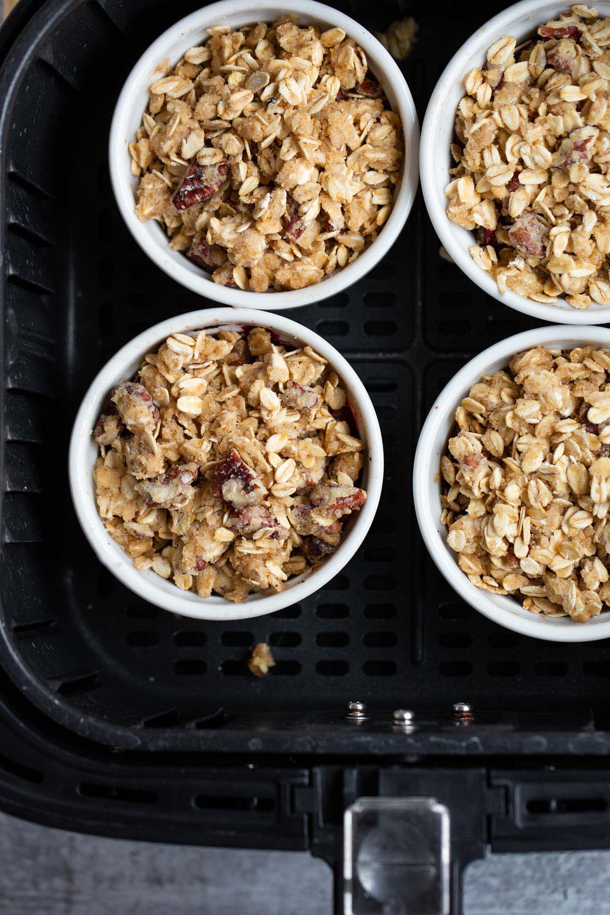 Adding crumble topping to the ramekins.