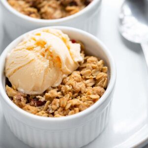 Air Fryer cranberry apple crisp in ramekins topped with ice cream.