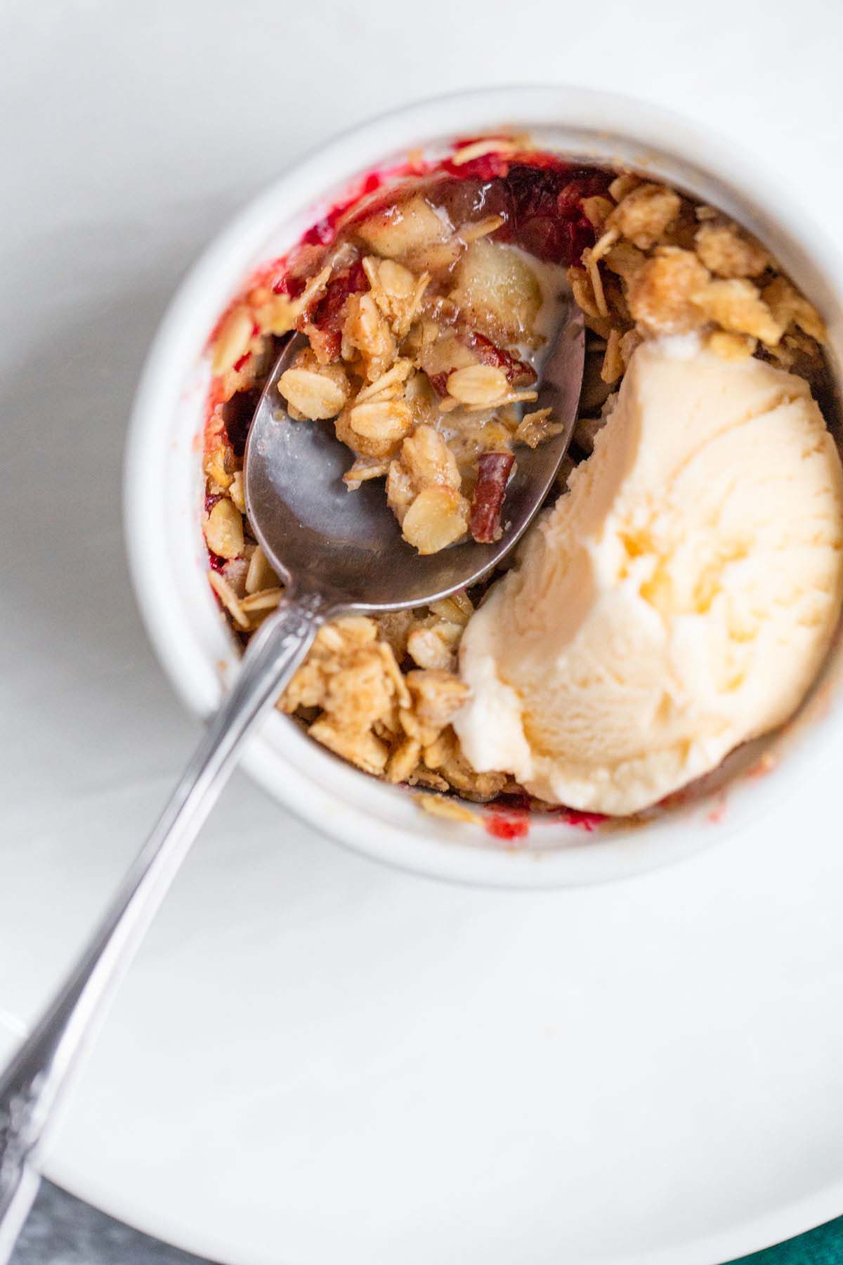 Apple cranberry crisp being eaten with ice cream on top.