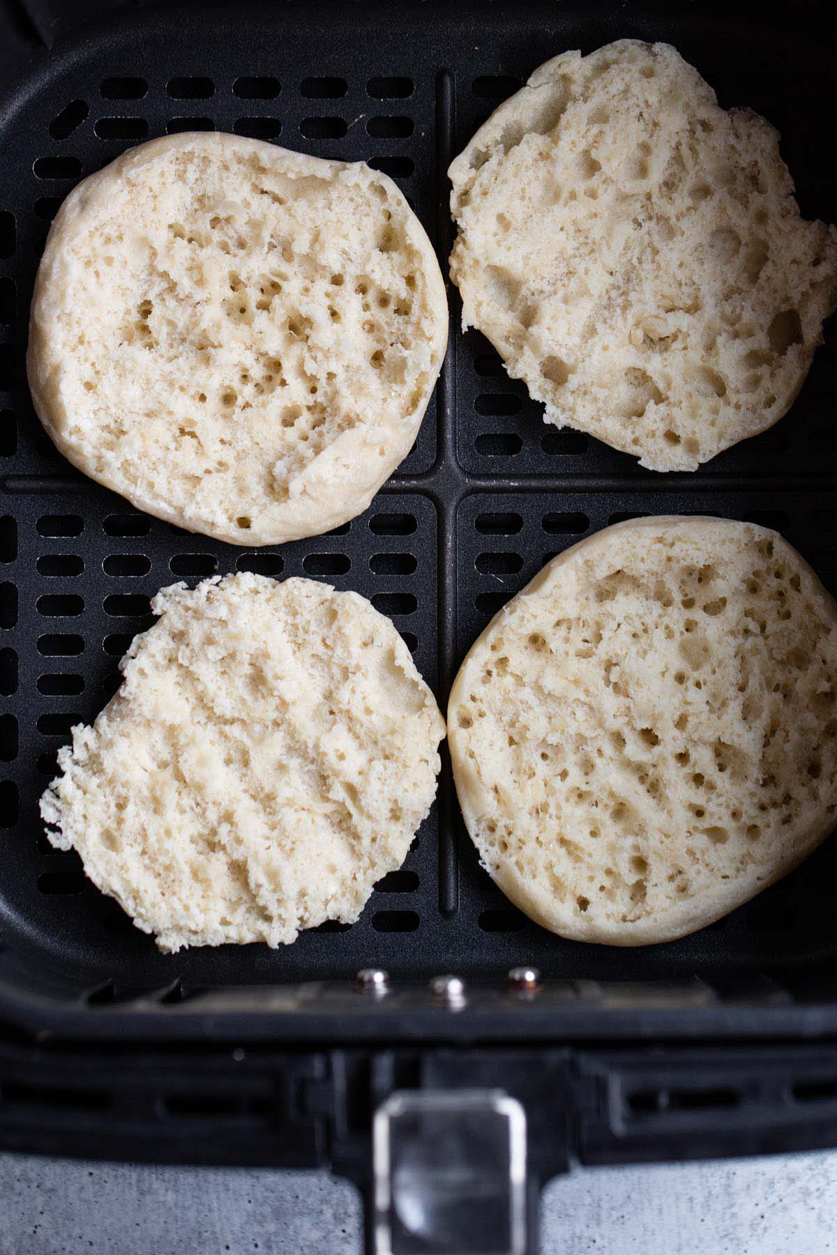 Untoasted English muffin in air fryer basket.