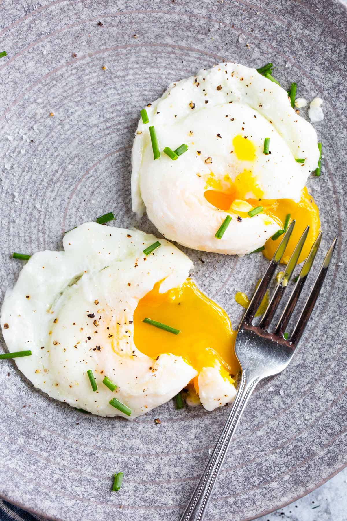 Two poached eggs with yolks broken.