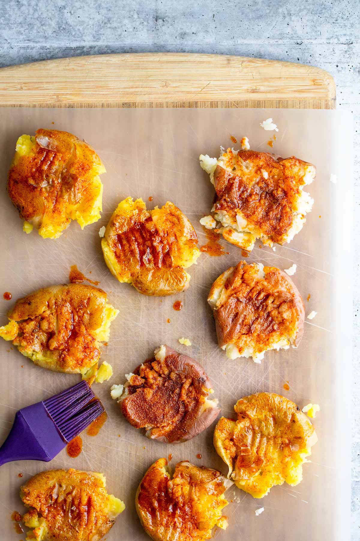 Brushing smashed potatoes with olive oil and paprika.