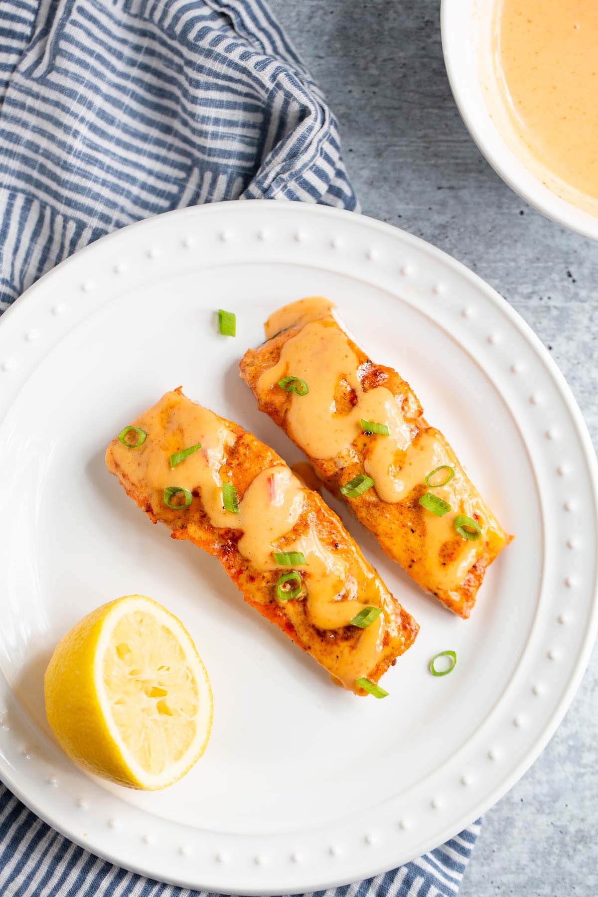 Salmon with bang bang sauce on a white plate.