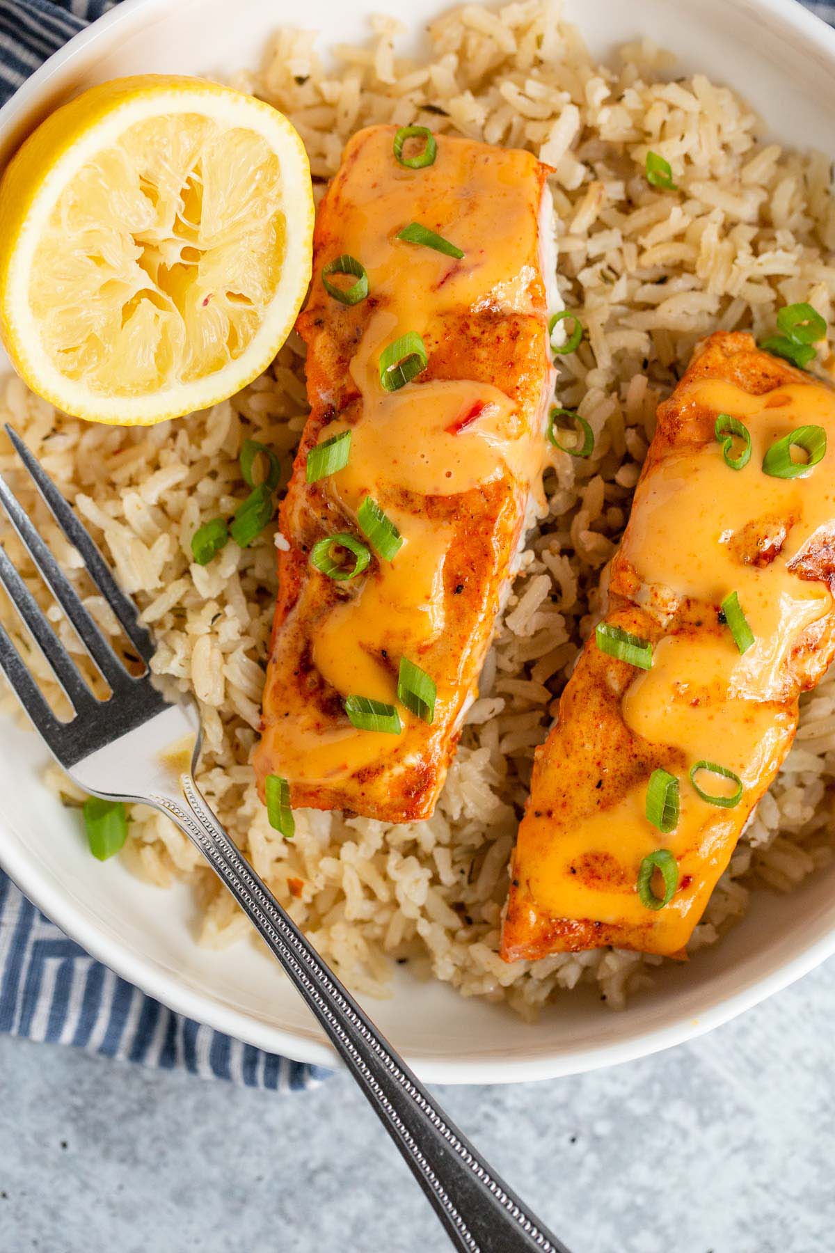 Cooked salmon topped with bang bang sauce in a bowl with rice.