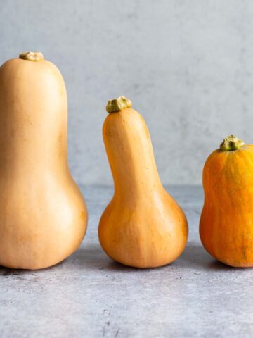 Butternut squash, honeypatch squash, and honeynut squash next to each other.