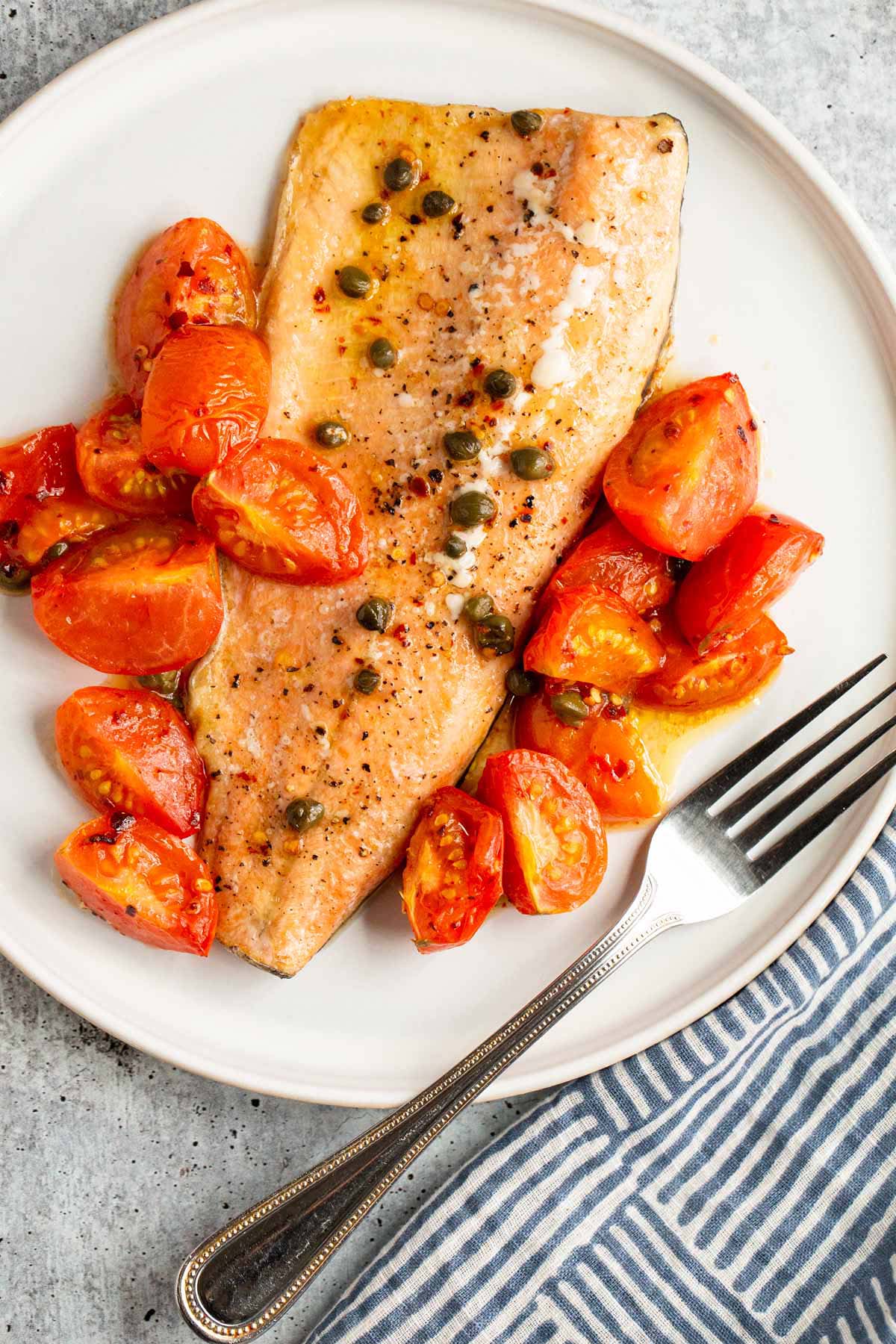 Cooked rainbow trout with tomatoes and capers.