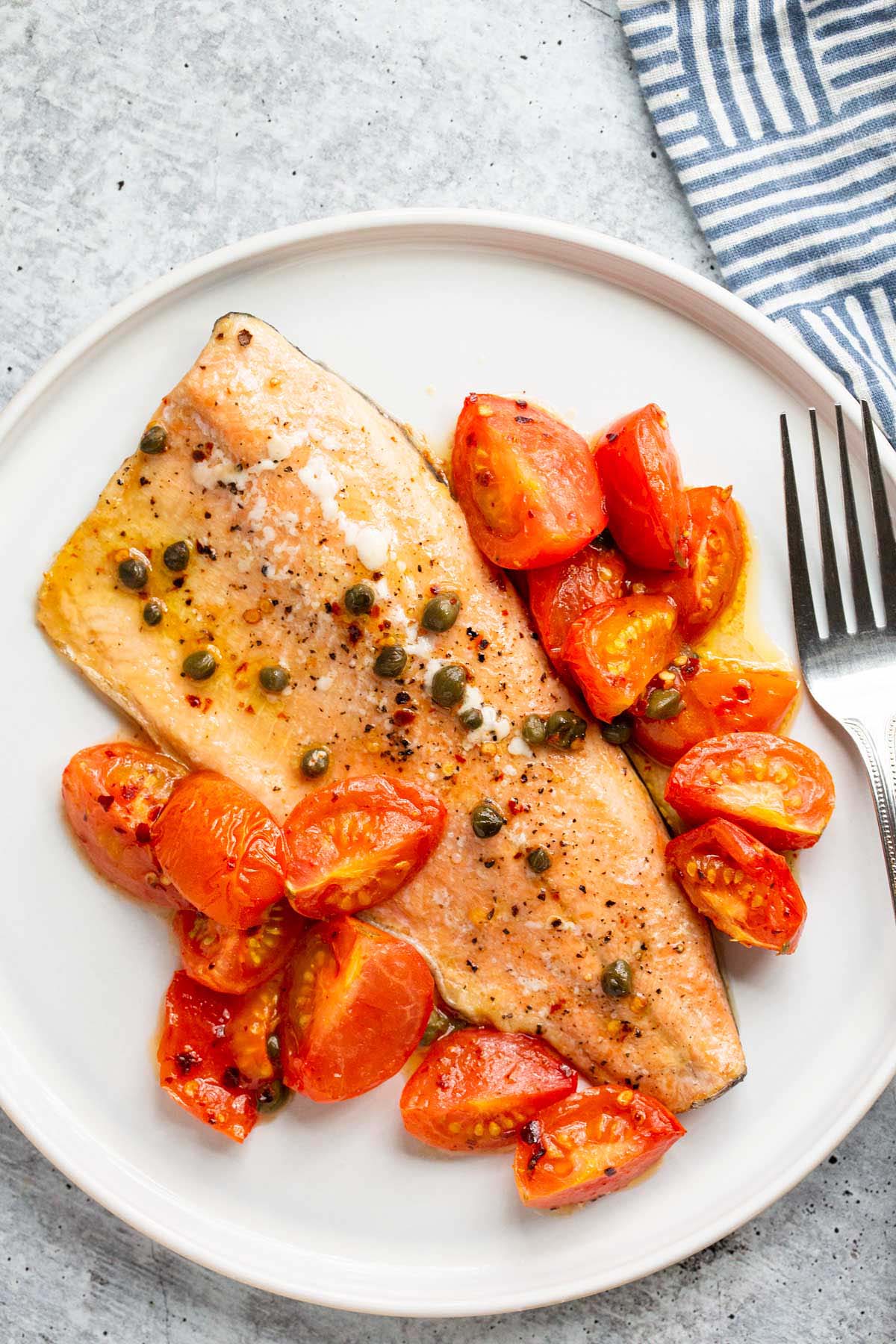 Cooked rainbow trout with tomatoes and capers.