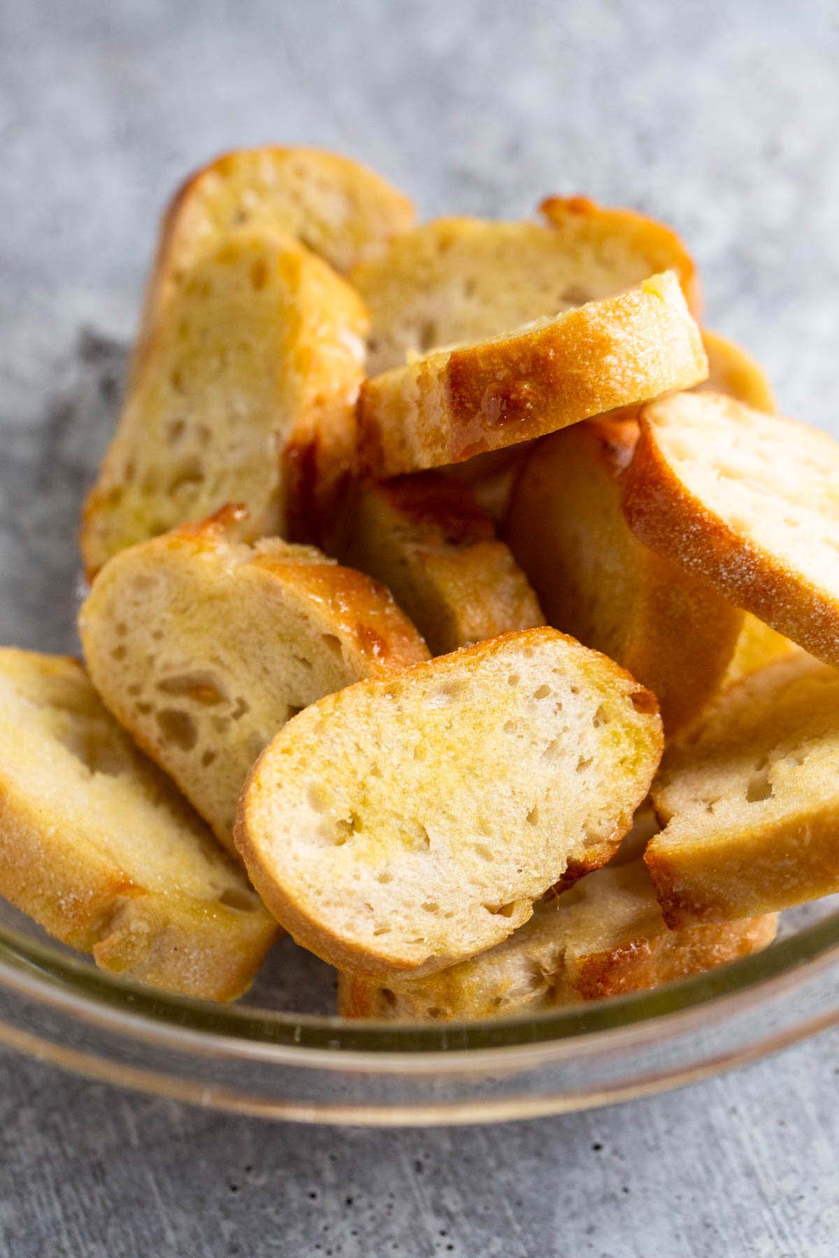 Bread slices in a bowl tossed with olive oil.