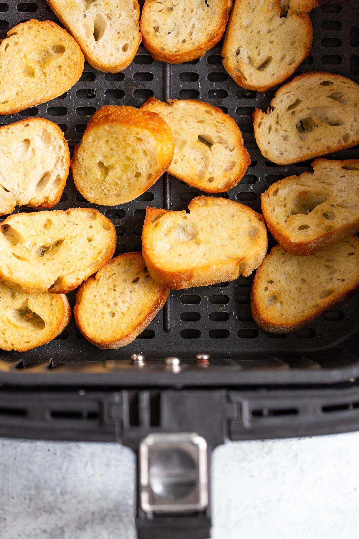 Crostini in air fryer basket.