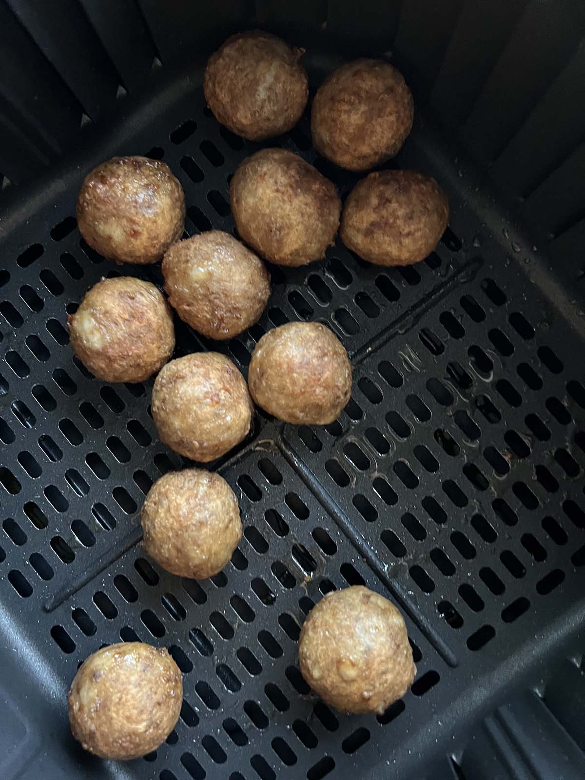 Cooked ikea meatballs in air fryer basket.