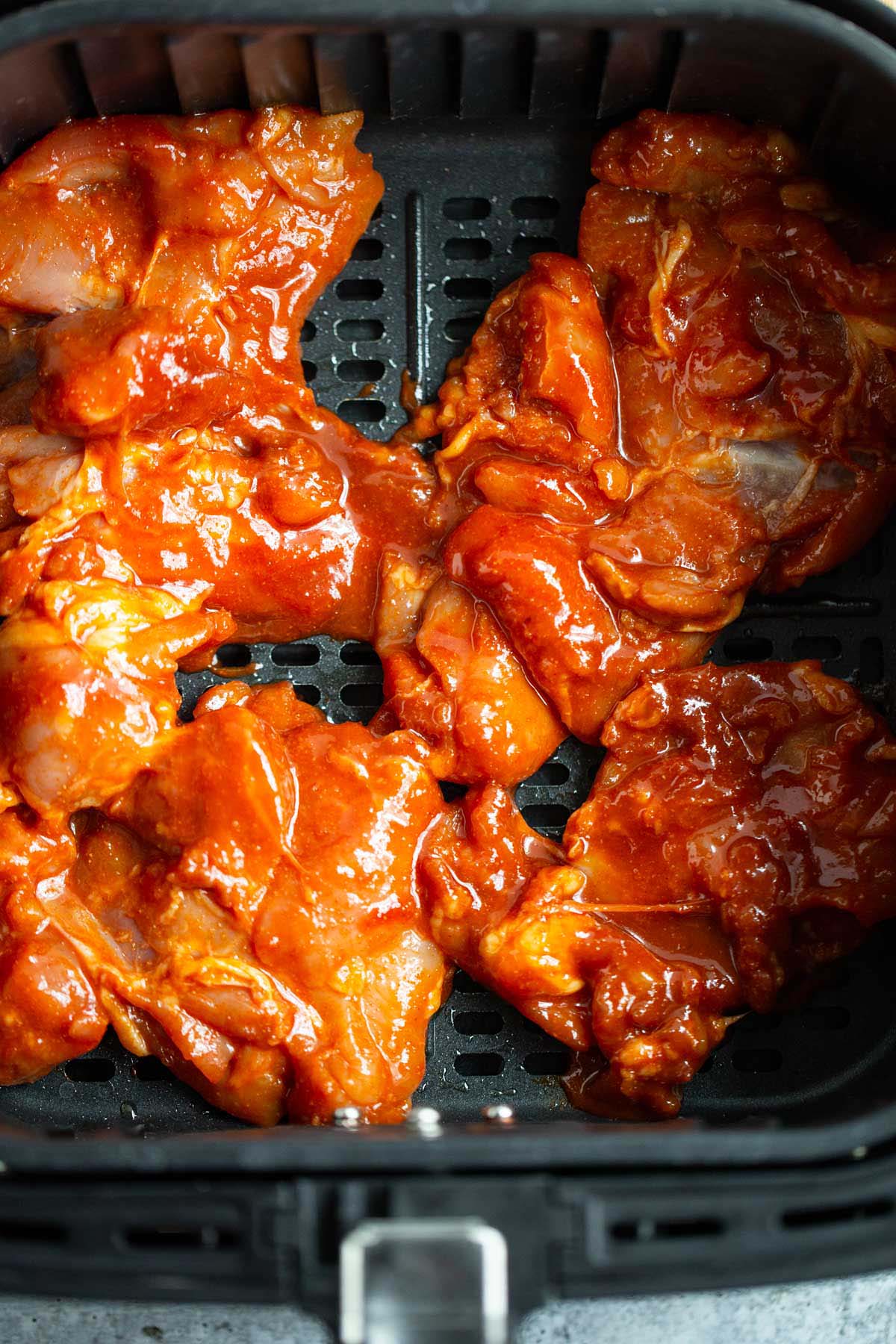 Gochujang chicken thighs in air fryer basket.