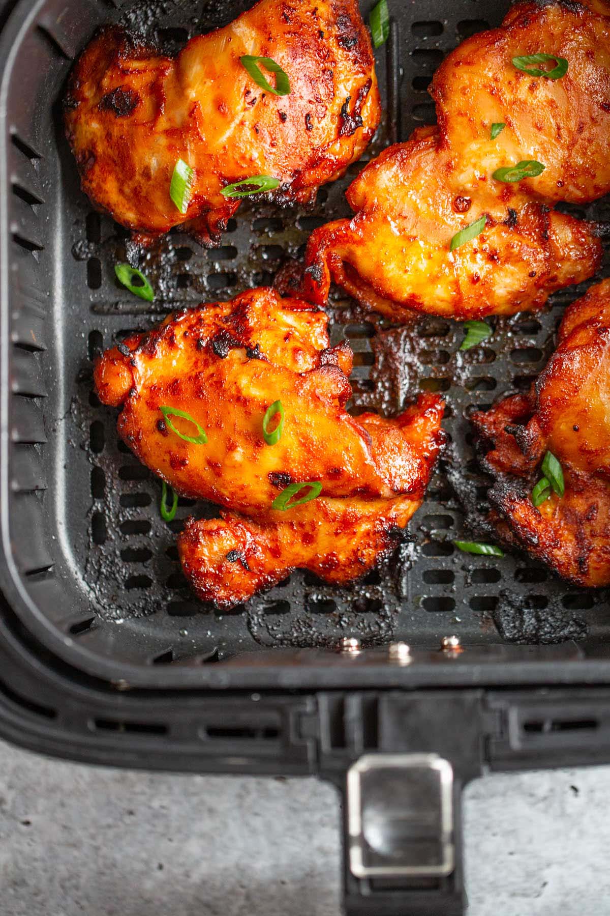 Gochujang chicken thighs in air fryer basket.