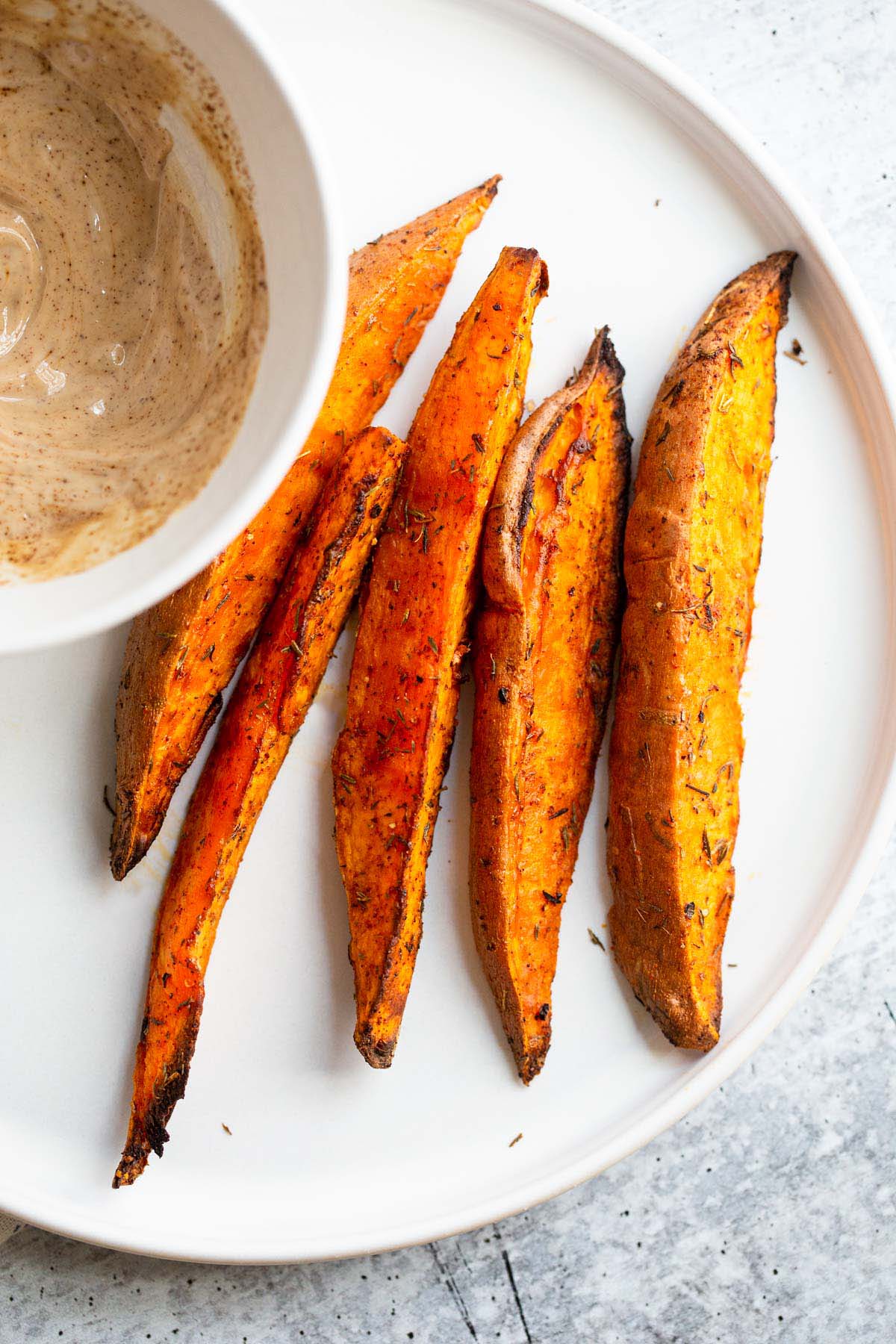 Air fried sweet potato wedges on a white plate.