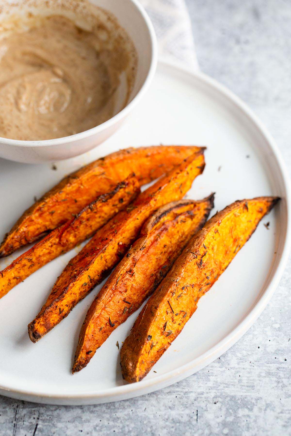 Air fried sweet potato wedges on a white plate.