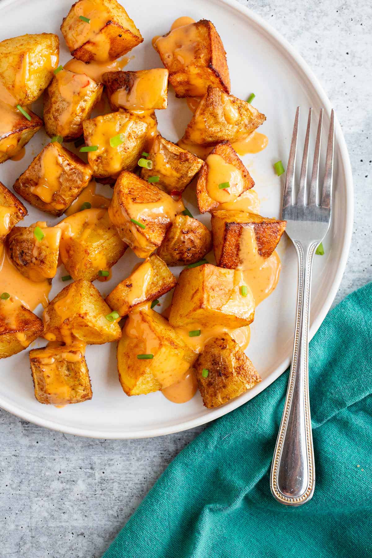 Bang bang potatoes on a white plate with a fork.