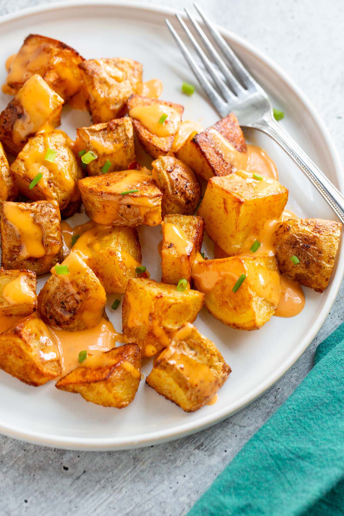 Bang bang potatoes on a white plate with a fork.