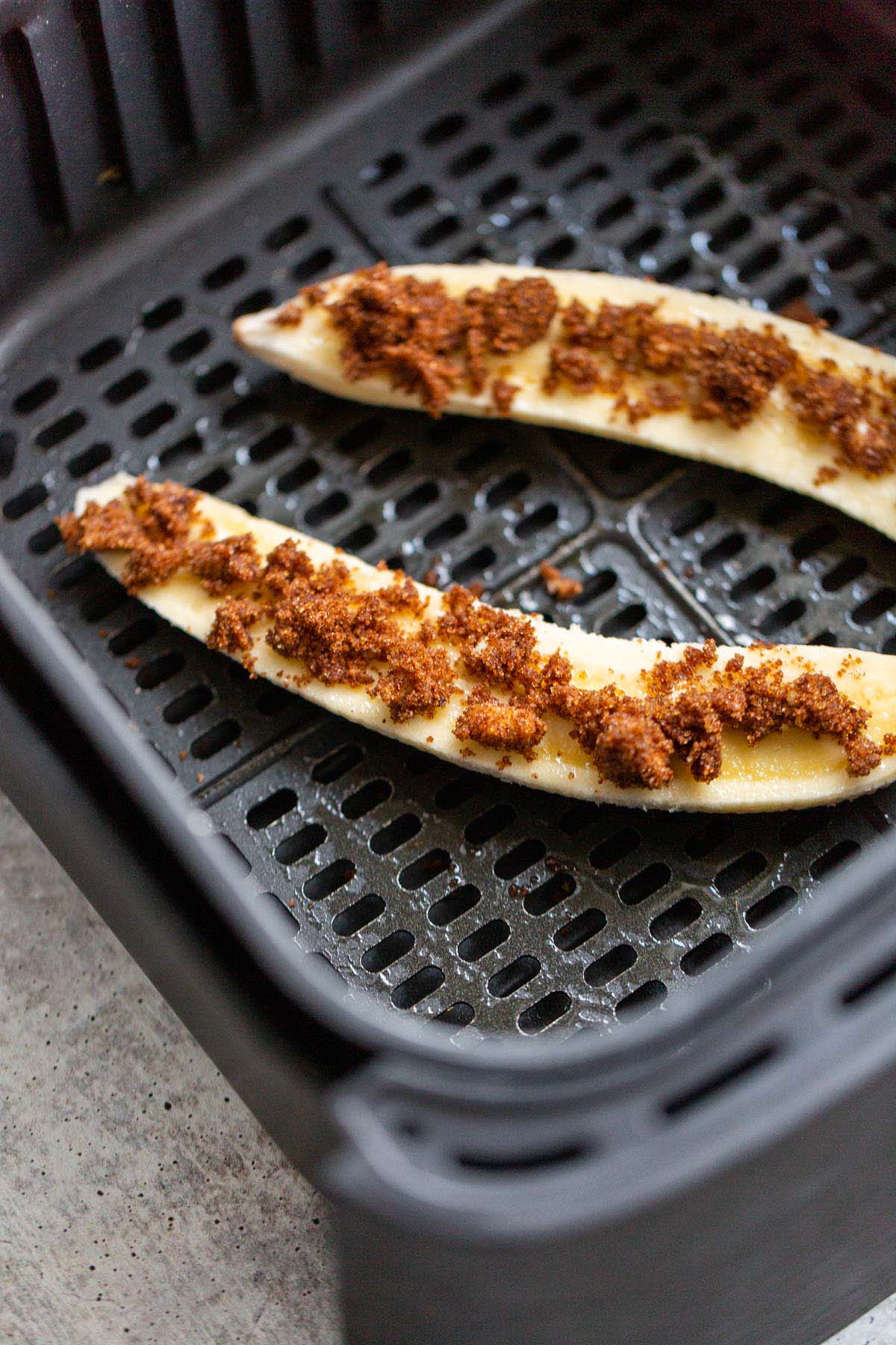 Banana topped with brown sugar mixture in air fryer basket.