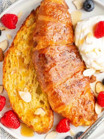 Air fryer croissant french toast with whipped cream and berries.