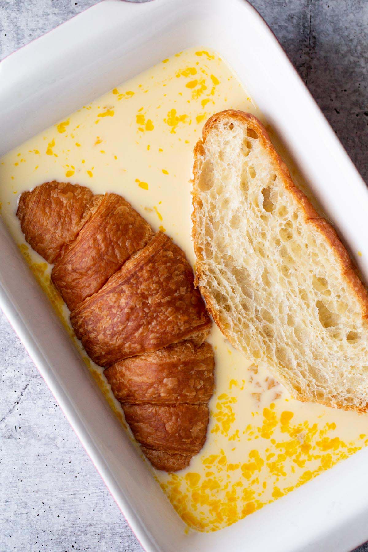 Dipping a croissant into a custard mixture.