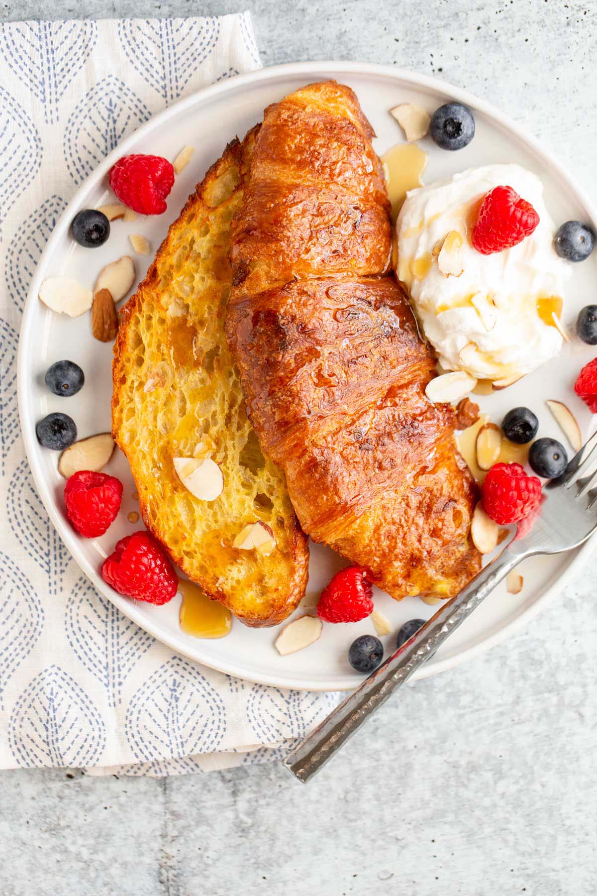 Croissant french toast topped with berries and whipped cream.