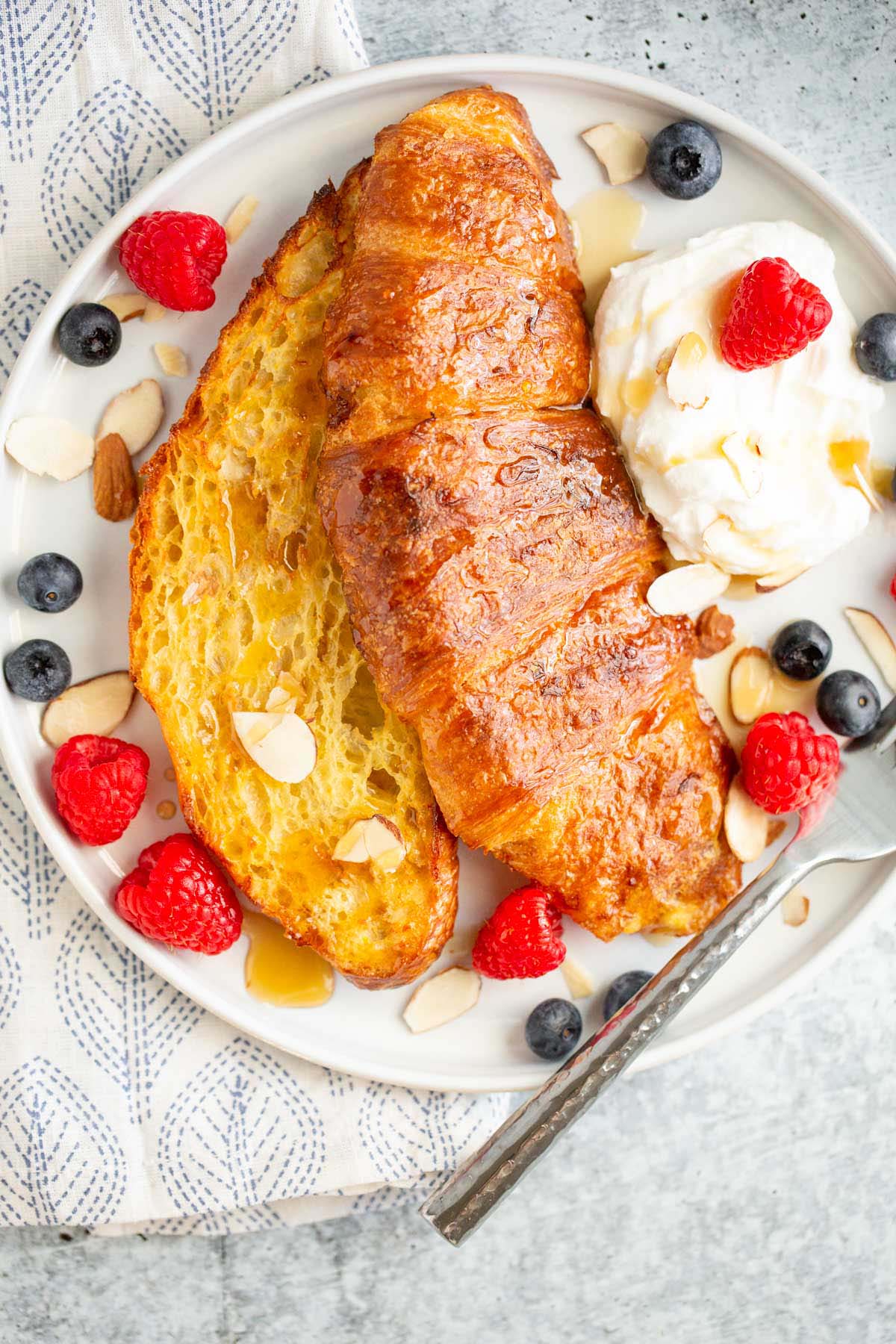 Croissant french toast topped with berries and whipped cream.